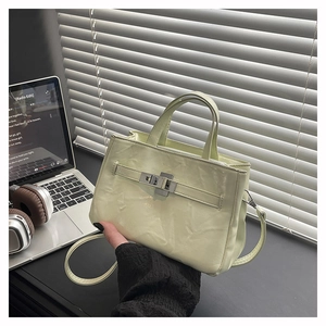 Détail du sac seau vert clair au fini brillant, fermoir rotatif argenté et texture plissée
