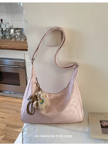 Detail of pink faux leather hobo bag with teddy charm and decorative stitching