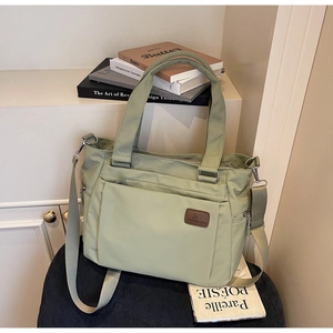 Detail view of the mint green crossbody tote bag showing functional pockets and logo patch