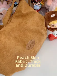Detail shot of the brown matte peach skin fabric texture and leather logo on tote bag