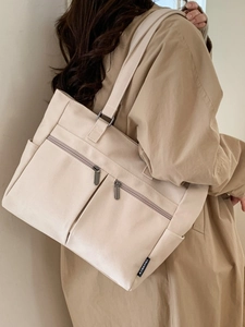 Large capacity beige canvas tote bag with front zipper pockets and side compartments