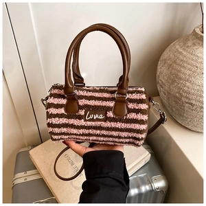 Detail of plush cylinder bag featuring pink stripes and Love label in travel scene