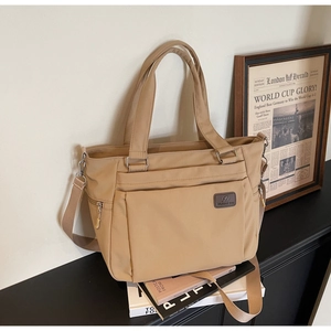 Close-up of khaki nylon tote bag with front flap pocket and adjustable wide shoulder strap
