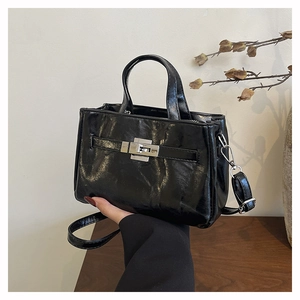 Détail du sac seau noir vintage avec fermoir rotatif argenté et texture en similicuir brillant