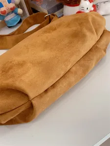 Detail view showing structured folded bottom design of a brown matte suede tote bag