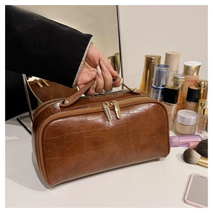 Detailed view of brown crocodile texture PU leather makeup bag with dual gold zippers