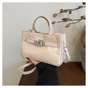 Détail d'un sac seau beige en cuir texturé avec un fermoir rotatif métallique élégant