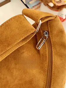 Detail of silver metal ring connecting thick suede strap on a brown crossbody bag
