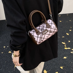 Side view of pink plaid cylinder bag with star print and brown shoulder strap