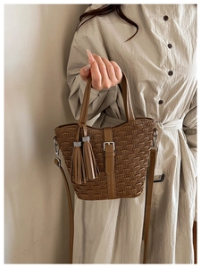 Detailed shot of brown pleated bucket bag with tassel and adjustable shoulder strap
