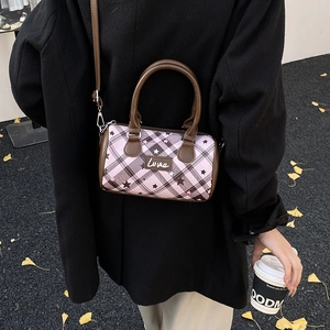 Detail of pink plaid Boston bag with star patterns and Love label on street background