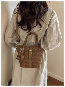 Brown woven texture bucket bag styled with a beige trench coat and fringe detail
