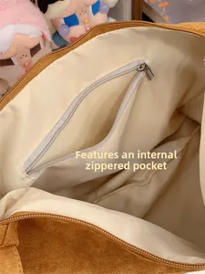 Close-up of the internal zipper pocket and beige lining of the brown suede tote bag