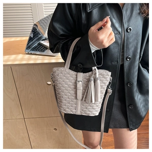Detail of light beige pleated handbag with elegant tassels and textured fish scale pattern