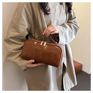 Detail of brown crocodile pattern storage bag with gold metal double zippers and top handle