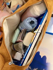 Top view of spacious interior of brown suede tote bag filled with daily essentials