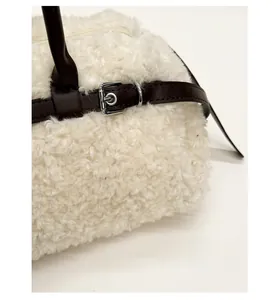 Detail of white faux shearling tote bag with leather strap and silver metal buckle