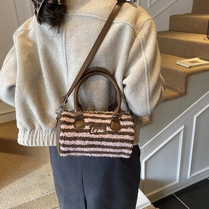 Detailed texture of plush striped Boston bag with brown leather handles and Luna tag