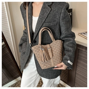 Detail of beige bucket bag with pleated texture and stylish tassel decoration