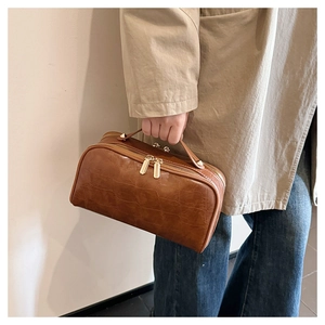 Detailed view of brown crocodile pattern cosmetic bag with golden double zippers