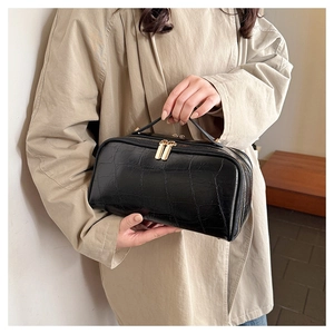 Close-up of black crocodile pattern leather travel pouch with gold dual zippers