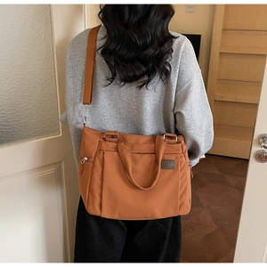 Détail de la bandoulière textile large réglable sur le grand sac cabas caramel