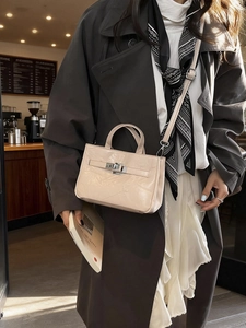 Sac seau élégant abricot avec fermoir tournant en métal et bandoulière dans un café