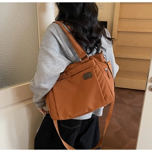 Detail view of large brown nylon tote bag with side zipper pocket and shoulder strap