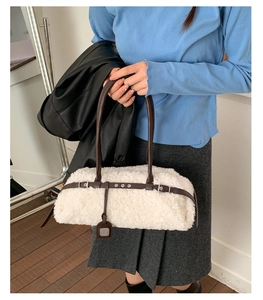 Detail of white faux shearling tote bag with brown leather straps and silver buckle