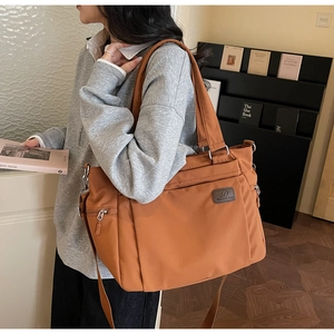 Detail of caramel nylon tote bag showing side compartments and adjustable strap