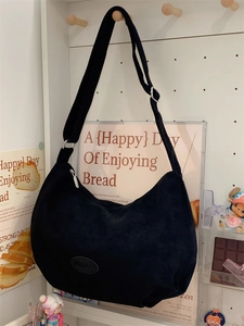 Detail of black corduroy crescent tote bag showing the logo and adjustable strap buckles