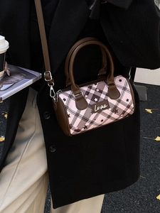 Pink and brown checkered Boston bag with star prints and Love tag in a street setting