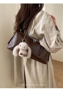 Detail der dunkelbraunen Retro-Boston-Tasche mit Plüsch-Kaninchen-Anhänger
