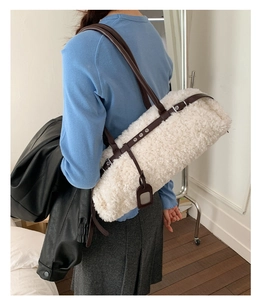 Detail of plush cream lamb wool tote with adjustable brown leather straps on model