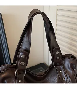 Detail of dark brown tote bag with glossy leather texture and silver metal rivets
