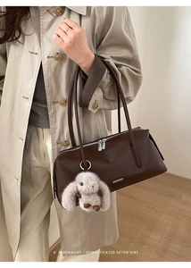 Nahaufnahme der dunkelbraunen Boston-Tasche mit langen Henkeln und süßem Hasen-Anhänger
