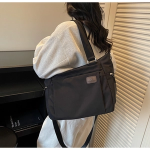 Side view of large black nylon tote bag on shoulder showing multi-pocket design