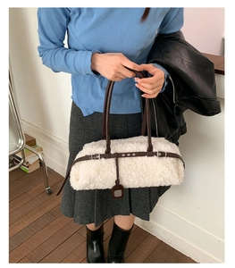 Detail of white plush tote bag with brown leather straps and silver buckle accents