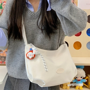 Detail of off-white dumpling bag with cute charms and a small oval brand tag