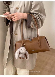 Detail der dunkelbraunen Leder-Tote-Bag mit Metall-Reißverschluss und Plüsch-Hasenanhänger