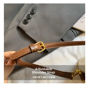 Detail of adjustable dark brown leather shoulder strap with gold-tone metal buckle