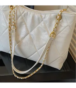 Detailed view of the white quilted leather tote bag featuring a gold chain shoulder strap