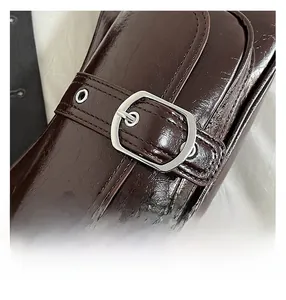 Close-up of dark brown oil wax leather bag with silver metal buckle and fine stitching