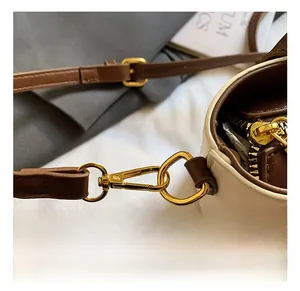 Detailed view of the gold-tone metal hook and brown leather strap on a bucket bag