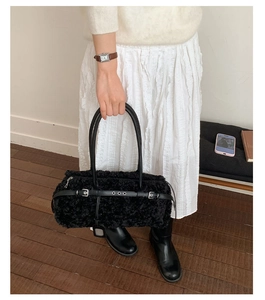 Close-up of black fuzzy lamb wool cylinder tote bag with leather strap and silver buckle