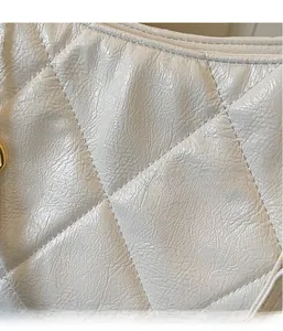 Close-up of white quilted leather texture with glossy finish and diamond stitching