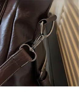 Detail of silver metal D-ring and spring hook on retro brown faux leather tote bag