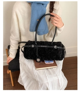 Detail of plush black lamb wool cylindrical shoulder bag with leather strap and handle