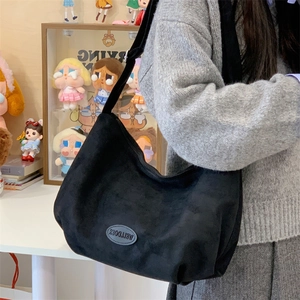 Detail of black frosted tote bag featuring adjustable strap and circular logo patch