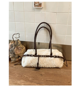 Detail of white plush faux shearling tote with brown leather straps and vintage buckle